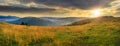 Valley in mountains on hillside under sky with clouds at sunset