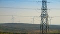 Valley with rotating wind turbines and high voltage power lines. Concept of green electricity, renewable power and energy, modern Royalty Free Stock Photo