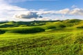 valley view in a green shiny field with green grass and golden sun rays, deep blue cloudy sky on a background , green rural hills Royalty Free Stock Photo