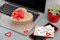 Valnetines day gift bos with a bow on laptop near card BE MY VALENTINE