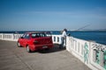 Man with fishing rod is fishing on seafront of Valparaiso city. Red Daewoo car is parked on embankment