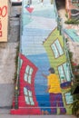 Stairway covered under colorful graffiti, with a person holding a kite with the flag of Chile, in Valparaiso, Chile