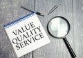 value quality service symbol on notepad and glasses and magnifying glass Royalty Free Stock Photo