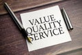 value quality service words on paper sheet and pen on wooden background Royalty Free Stock Photo