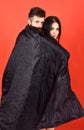 Vampire in cloak behind devil girl. Man and woman dressed like vampire, demon, red background. Couple in love Royalty Free Stock Photo