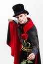 Vampire Halloween Concept - Portrait of handsome caucasian Vampire holding red beautiful rose on white studio background Royalty Free Stock Photo