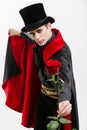 Vampire Halloween Concept - Portrait of handsome caucasian Vampire holding red beautiful rose on white studio background Royalty Free Stock Photo