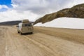 Van driving past snow pack.