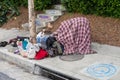 A homeless person huddles under a blanket on the sidewalk