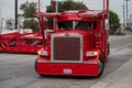 A red Peterbuilt truck car-carrier owned by Pete`s Auto Transport making a wide tur