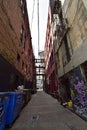 An narrow alleyway between colored old brick buildings and garbage containers at evening at the Vancouver downtown Royalty Free Stock Photo