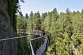 Visitors exploring the Capilano Cliff Walk through rainforest. The popular suspended walkways juts out from the granite cliff