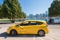 Orange taxi in Stanley Park with Vancouver Skyline in background