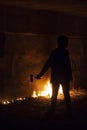 Vandal protester silhouette with molotov`s cocktail. Flaming wall on background