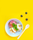 Vanila and strawberry ice cream with caramel and mint on white bowl with nuts and blueberries on yellow background. Three scoops, Royalty Free Stock Photo