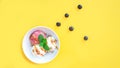 Vanila and strawberry ice cream with caramel and mint on white bowl with nuts and blueberries on yellow background. Three scoops, Royalty Free Stock Photo