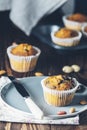 Vanilla caramel muffins in paper cups and bottles of milk on dark wooden background. Delicious cupcake with raisins, almonds and Royalty Free Stock Photo