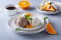 Vanilla and chocolate ice cream, cake and orange slices on a light wooden table