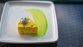 White square plate with an unusual cake in the form of a piece of cheese