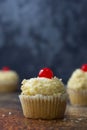 Vanilla cupcake with butter cream and cherry on top. Blue background. Celebrating, sweet food