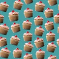 Vanilla cupcake in paper cup with pink frosting and cherry pattern on teal background