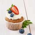 Vanilla cupcake with ripe strawberry and blueberries Royalty Free Stock Photo