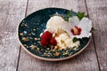 Vanilla ice cream with mint and pretty flower. A bowl of icecream and pink raspberries on a wooden background. Cold summer snacks.