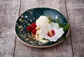 Vanilla ice cream with mint and pretty flower. A bowl of icecream and pink raspberries on a wooden background. Cold summer snacks.