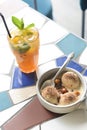 Vanilla Ice cream scoops with cocoa powder in a white bowl on the table. One glass of fruit cocktail. Royalty Free Stock Photo