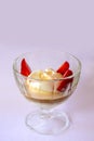 Vanilla ice cream with strawberries and chocolate sauce in a glass bowl over pink background. Royalty Free Stock Photo