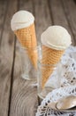 Vanilla ice cream in waffle cone on rustic wooden background Royalty Free Stock Photo
