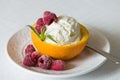 Vanilla Icecream with raspberry, summer dessert. Delicious sunday scoop in an orange half on a white plate Royalty Free Stock Photo