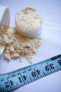 Vanilla protein powder in scoop with a tape measure Royalty Free Stock Photo