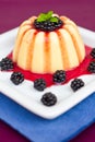 Vanilla pudding on a plate decorated with blackberries and mint