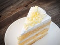 Vanilla sponge cake with cream and white chocolate decorate. Sliced piece of cake on white plate. Served on wooden table. Royalty Free Stock Photo