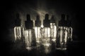 Vape concept. Smoke clouds and vape liquid bottles on dark background. Light effects. Useful as background or vape advertisement. Royalty Free Stock Photo