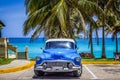 American blue Buick Eight classic car parked under palms on the beach in Varadero Cuba -Serie Cuba Royalty Free Stock Photo