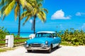 American blue 1955 classic car with a white roof parked direct on the beach in Varadero Cuba