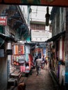 Varanasi, or Benares, Uttar Pradesh, India - An old man walking on a street lined with shops selling colorful clothes and fabrics.