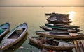 Varanasi, India: Bunch of old wooden colorful boats docked in the bay of Ganges river bank during sunset sunrise against foggy Royalty Free Stock Photo