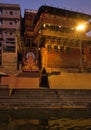 Varanasi, India: Bunch of wooden boat docked in ganges river next to empty ghat and ancient building before