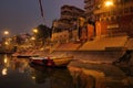 Varanasi, India: Bunch of wooden boat docked in ganges river next to empty ghat and ancient building before