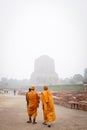 VARANASI, INDIA - DECEMBER 2, 2016: Buddhist monks and tourists come to visit and pray in the misty morning at Dhamekh Stupa. Royalty Free Stock Photo