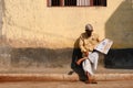 Unidentified Man comfortably sits and reads Indian newspaper on the street of Varanasi