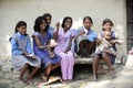 Many Indian girls sit together on a cement seat. They held the money and laugh happily