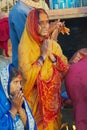 Woman pilgrim prays at the bank of the Holy Ganges river at sunrise with other pilgrims at the background in Varanasi, India.