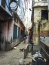 Varanasi, India: Narrow gali or lane or street between old buildings with messy electrical wire and a man