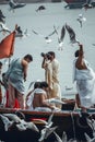 Varanasi, India, 16 november, 2019 / Boat passing on the Ganges with curious persons on top; a fat man in white feeding the birds,