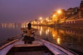 Varanasi, India: A man rowing a wooden paddle on a boat before sunrise in ganges river against illuminated Royalty Free Stock Photo