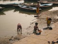 Young boys and adult man washing their clothes with hands in the muddy water of sacred Ganges River